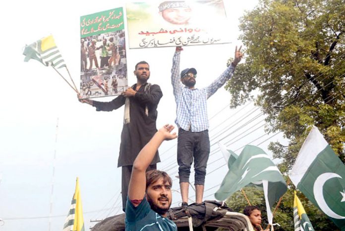 لاہور: احتجاج کے دوران دو نوجوان برہان مظفر وانی کا کتبہ اٹھائے کشمیریوں سے یکجہتی کررہے ہیں